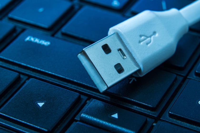 Ein weißer USB-Stecker liegt auf den Tasten einer schwarzen Tastatur.