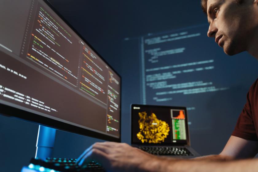 Nahaufnahme eines konzentrierten Programmierers, der im Heimbüro für ein Softwareentwicklungsunternehmen an der PC-Programmierung arbeitet, Code für Anwendungen oder Website-Design schreibt.