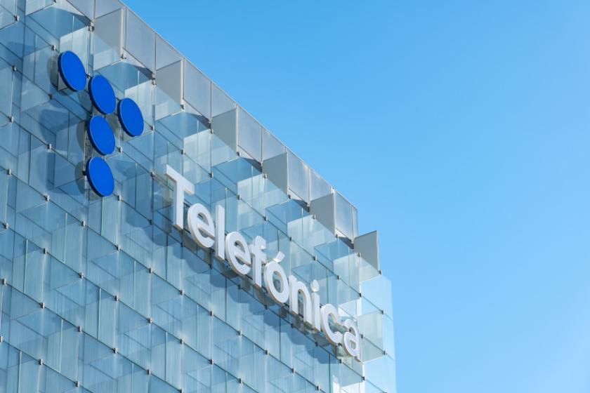 Glasfassade mit Dachkante des Telefónica-Hauptquartiers, an der das Telefónica-Logo zu sehen ist.