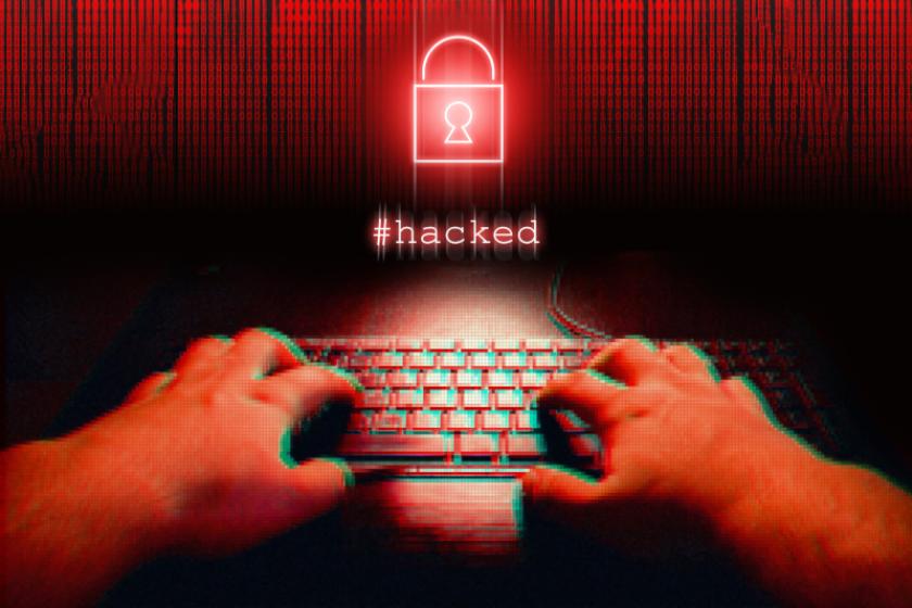 Hände tippen in rot gefärbt auf einer Tastatur vor einem stilisierten Vorhängeschloss und dem Schriftzug Hacked..