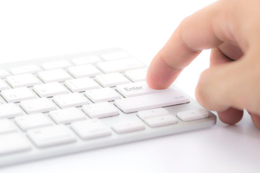 Finger von Mann will Enter Taste von einer Computer-Tastatur berühren.