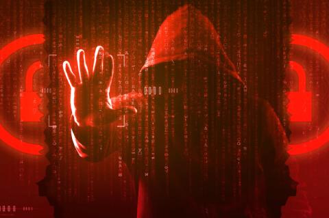 Ein Mann in einem Kapuzenpulli steht als Hacker vor einer roten Wand aus Programmiercode und streckt seine Hand danach aus.