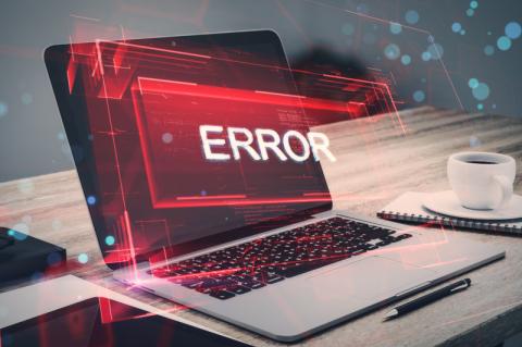 Ein aufgeklappter Laptop steht auf einem Tisch, über dem Bildschirm erscheint in einem roten Kasten der Text "Error".