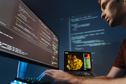 Nahaufnahme eines konzentrierten Programmierers, der im Heimbüro für ein Softwareentwicklungsunternehmen an der PC-Programmierung arbeitet, Code für Anwendungen oder Website-Design schreibt.