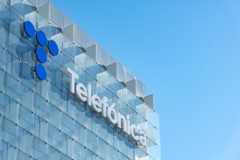 Glasfassade mit Dachkante des Telefónica-Hauptquartiers, an der das Telefónica-Logo zu sehen ist.
