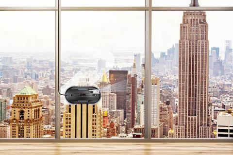 Fensterputzroboter HOBOT im Einsatz an einer Glasfassade mit Blick auf eine Großstadtskyline; das Gerät säubert die Fenster automatisch.