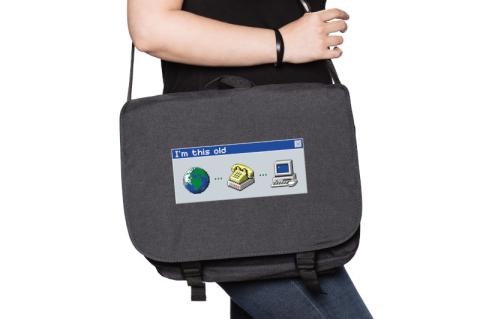 Eine Umhängetasche hängt über der Schulter einer Person. Auf der Tasche sind pixelige Computersymbole zu sehen: eine Weltkugel, ein Modem und ein PC.