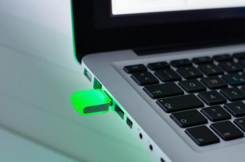 Ein grün leuchtendes USB-LED-Device ist an einem Laptop eingesteckt.