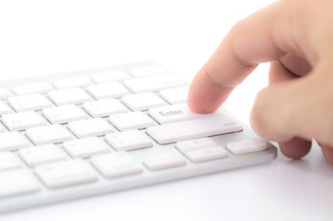 Finger von Mann will Enter Taste von einer Computer-Tastatur berühren.