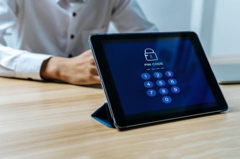 Ein Tablet steht auf einem Tisch mit einer Aufforderung zur PIN-Eingabe auf dem Bildschirm.